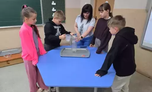 Uczniowie przy stoliku robią doświadczenie